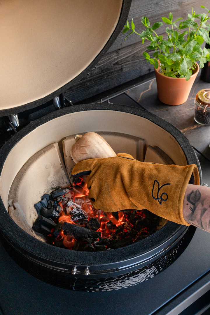 Roostr Buitenkeuken barbecue handschoen leer bruin met bbq op de achtergrond